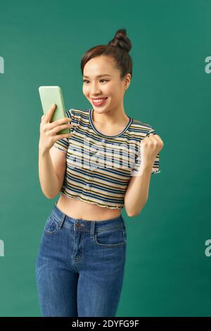 Asian woman play mobile game on smartphone and win, Stock Photo