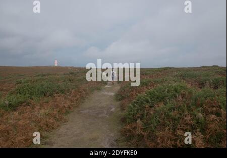 Two People Walking Along a Footpath on the Moorland of Chapel Down Heading Towards the Day Mark on the Island of St Martin's in the Isles of Scilly Stock Photo