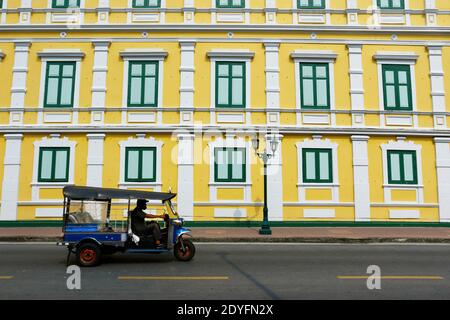 A tuk tuk in the street of bangkok with an architectural view of with green window on an asian building Stock Photo