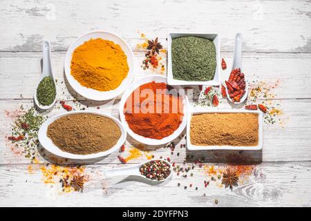 Various spices in a bowls on white wooden background. Top view with copy space. Cooking ingredients and condiments concept. Stock Photo