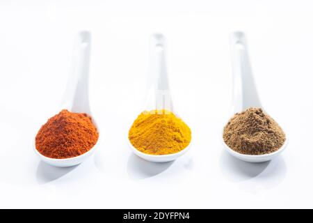 Three white spoons with paprika, turmeric and cumin on a white background. Cooking ingredients and condiments concept. Stock Photo