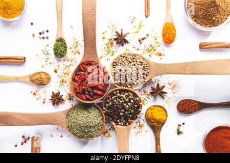 Variety of spices and herbs in spoons and bowls on white background. Top view. Cooking ingredients and condiments concept. Stock Photo