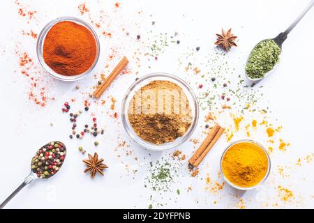 Variety of spices and herbs in spoons and bowls on white background. Top view. Cooking ingredients and condiments concept. Stock Photo