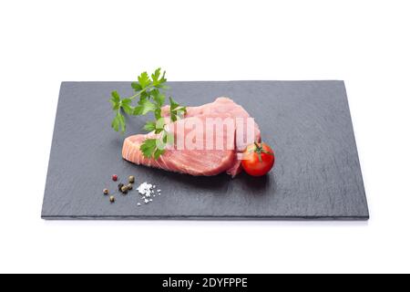 Fresh raw tuna fillets with seasoning, in a slate plate on  white background. Stock Photo