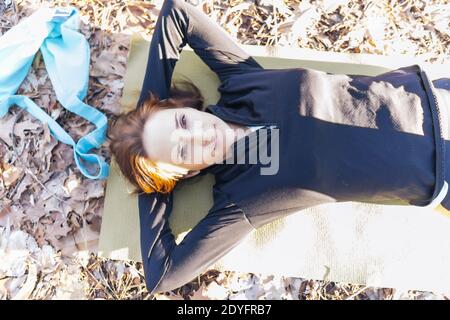 beautiful female woman lying relaxed on yoga mat after workout. relaxation and wellness concept Stock Photo