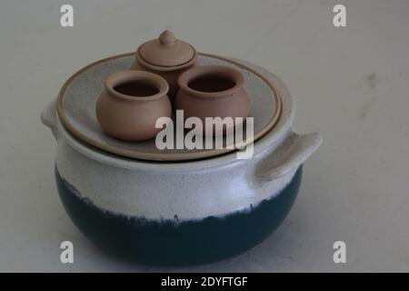 A closeup shot of clay dishes on a plate on a white and blue pan Stock Photo