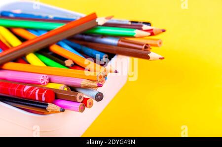 Lots of different colorful wooden crayons, many multi colored crayons mixed in a box container, closeup. Back to school, art class drawing supplies Stock Photo