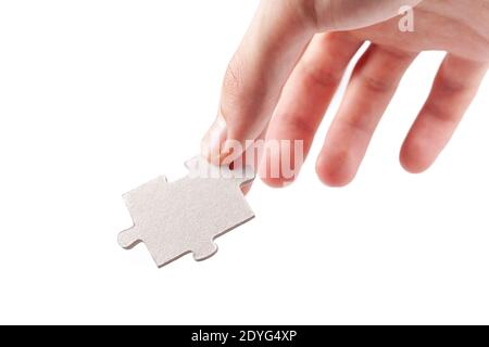 Hand holding a single blank empty jigsaw puzzle piece, laying, putting down from above gesture isolated on white, cut out. Fingers hold up last piece Stock Photo