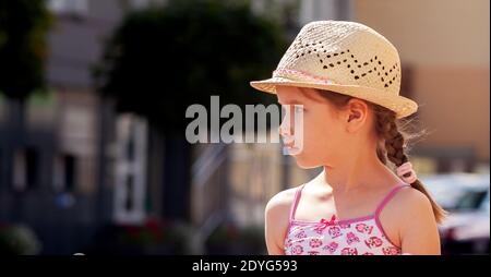 Little girl alone, school age child model looking right, copy space, text space on left, caucasian kid wearing panama hat, summer summertime travel Stock Photo