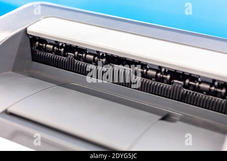 Simple home office laser printer extreme closeup, output tray macro, tray and rolls detail shot, office workspace equipment, modern printing device Stock Photo