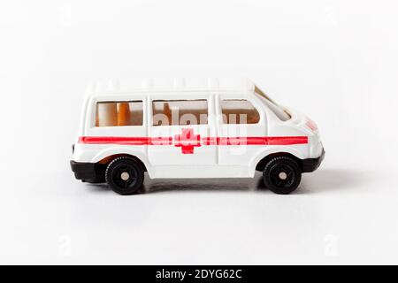 Simple small toy ambulance vehicle, mini sanitary car model with red cross on side, side view. Medical transportation automobile symbol, closeup Stock Photo