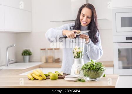 https://l450v.alamy.com/450v/2dyg6p4/smoothie-preparation-by-cutting-bananas-into-a-blender-by-a-woman-in-a-sweater-at-home-2dyg6p4.jpg