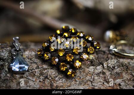 Close up of isolated old vintage brooch with yellow citrine quartz gemstones on natural tree trunk bark background Stock Photo
