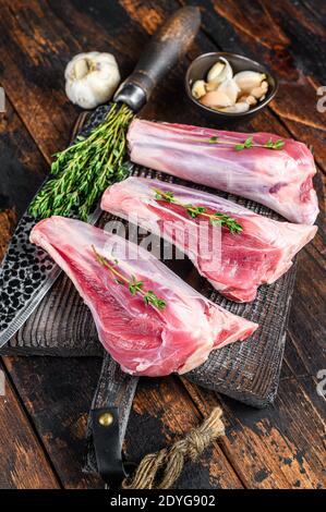 Raw veal shanks meat on a cutting board with herbs. Dark wooden background. Top view Stock Photo