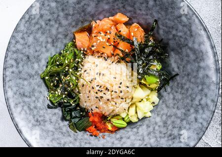 Hawaiian salmon poke bowl with seaweed, avocado, sesame seeds. Gray background. Top view Stock Photo