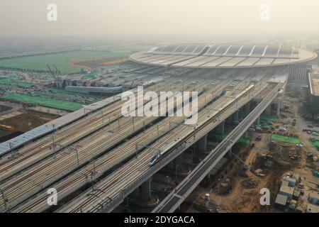 (201226) -- XIONGAN NEW AREA, Dec. 26, 2020 (Xinhua) -- Aerial photo shows a trial bullet train pulling out of the Xiongan Railway Station, which is along the railway linking Beijing and Xiongan New Area, in Xiongan, north China's Hebei Province, Dec. 26, 2020. The intercity railway section linking Beijing Daxing International Airport with Xiongan New Area will be officially put into operation on Sunday. Passengers can take high-speed trains from Beijing West Railway Station directly to Xiongan New Area with the shortest commuting time at 50 minutes. The travel time between the airport and Xi Stock Photo