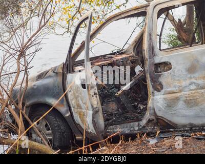 Front driver side of wrecked and burned out car on riverbank in New Orleans, Louisiana, USA Stock Photo