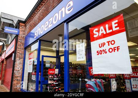 Sale posters in the window of Shoezone in Newcastle-under-Lyme, Staffordshire, during the Boxing Day sales. Boxing Day spending is expected to fall by more than a quarter compared with a year ago, after extensive new Covid-19 restrictions forced non-essential retailers to close. Stock Photo