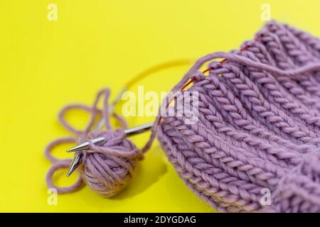 The cap is connected by circular spokes on the wire on a yellow background. Process of knitting. Best hobby. Stock Photo