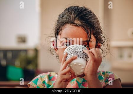 A young and school going kid enjoying and drinking her hot milk in a mug Stock Photo