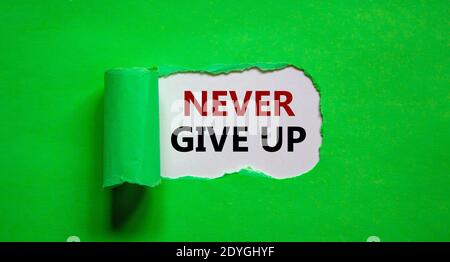 Never give up symbol. Words 'Never give up' appearing behind torn green paper. Business and 'never give up' concept. Copy space. Stock Photo