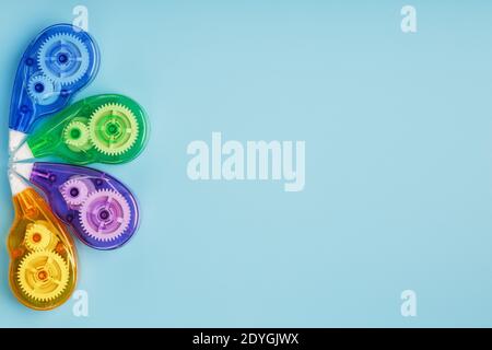 Stationery correction tapes are Multicolored on a blue background. Free space. The view from the top. Blue, green, yellow, lilac Stock Photo