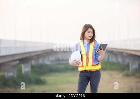 Woman Engineer With White Security Helmet holding tablet Standing On Construction Site Stock Photo