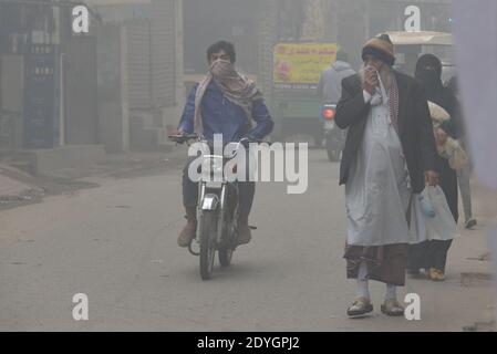 Pakistani Commuters make their way amid dense fog on a cold winter  in Lahore Stock Photo