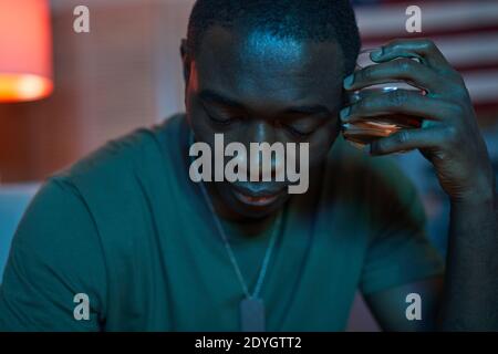 African man holding glass with alcohol and looking thoughtful and drunk Stock Photo