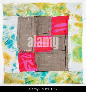 back side of sewn fragment of patchwork cloth from red and brown fabrics on white background Stock Photo