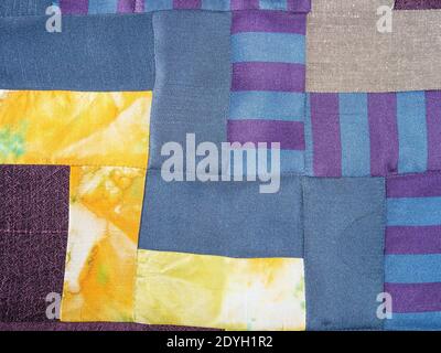 textile background - sewn fragment of patchwork cloth from blue and yellow fabrics Stock Photo