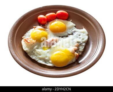 three fried eggs with bacon on brown ceramic plate cut out on white background Stock Photo
