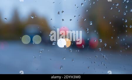 Raindrops on the glass against the abstract background of light; night streets seen through a window with raindrops Stock Photo
