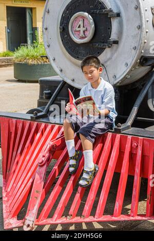 Huntsville Alabama,Depot Museum built 1860 train station,Asian boy sitting reading locomotive cowcatcher, Stock Photo
