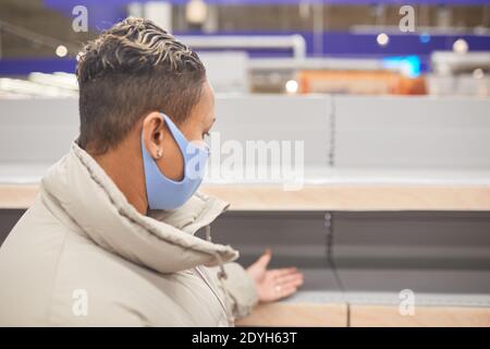 Rear view of woman in short hair and in protective mask standing in the mall Stock Photo