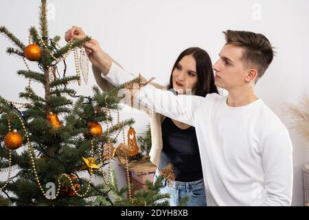 The bride and groom will continue to decorate the Christmas tree. Decoration of a Christmas tree for Christmas in December. Stock Photo