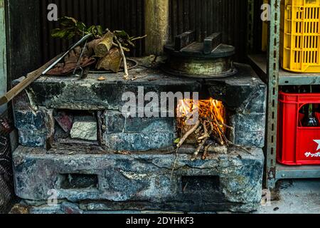 Traditional wood-fired stove for cooking rice, Rakan Restaurant, Izu Peninsula. Traditional Japanes Rice Cooking over open Fire by Atsuko Kato Stock Photo