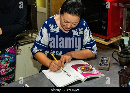 Rakan, a kaiseki restaurant run by chef Atsuko Kato, on the Izu Peninsula, Japan. Atsuko Kato writes a calligraphic dedication in her book. Stock Photo
