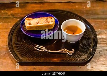 Rakan, a kaiseki restaurant run by chef Atsuko Kato, on the Izu Peninsula, Japan. A dessert cake sits on a ceramic plate by artist Chihiro Kato, served with tea. Stock Photo