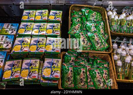 Packaged wasabi specialities are stacked on a shelf at the Izu Wasabi Museum in Kannami, Japan, including candied wasabi pieces in printed boxes and pickled wasabi in foil pouches. Stock Photo