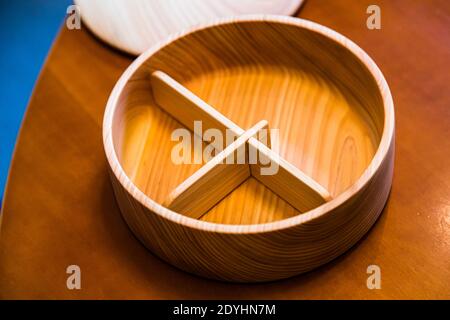 An empty round, three-compartment bento box made of light wood stands ready on the table to be filled – Kayoko Kawamura's bento workshop, Izunokuni, Izu Peninsula, Japan. Stock Photo