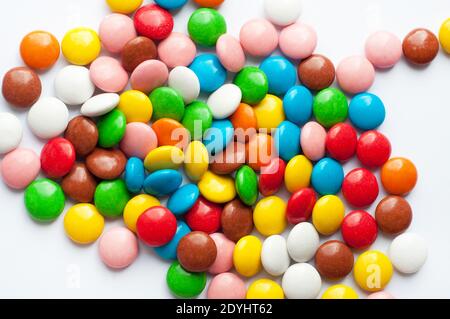 Colored round candies on a white background. Chocolate candies covered with multicolored sugar glaze. Stock Photo