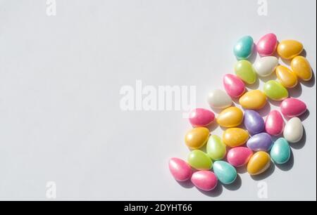 Colored candies in the form of eggs on a white background. Chocolate Easter candies covered with multicolored sugar glaze. Stock Photo