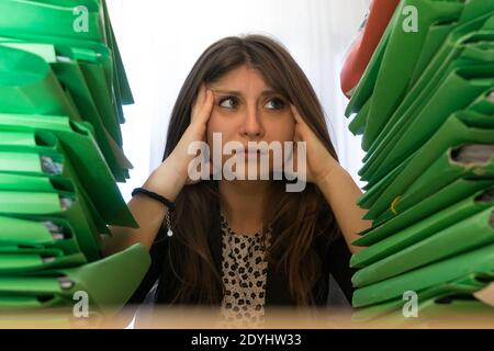 Office clerk stressed between two massive stacks of file folders to attend to. Employee stress concept. Stock Photo
