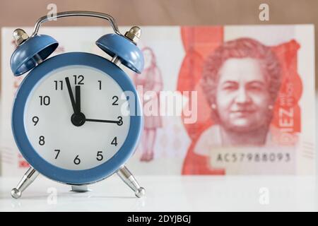 Colombian banknote, ten thousand pesos, alarm clock set for five to twelve, economic and business concept Stock Photo