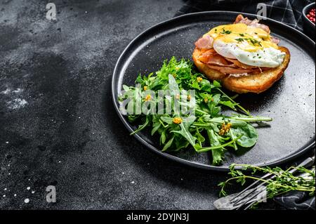 Breakfast Burger with bacon, egg Benedict, hollandaise sauce on brioche bun. Black background. Top view. Copy space Stock Photo