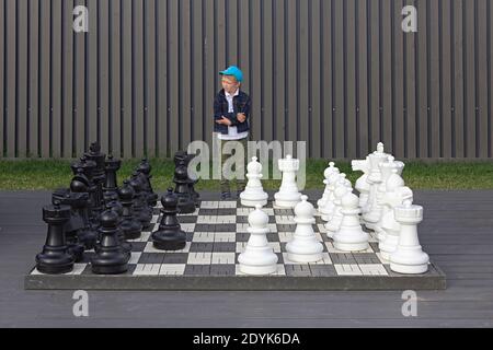 Saint-Petersburg, Russia, July 9, 2017. A young boy thinking about the move in chess, big street outdoor chess board, consept of making choice Stock Photo