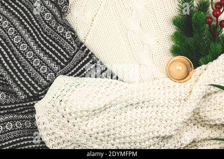 Winter cozy background, woolen and knitted sweater, fir branch with red berries and candle, composition with copy space Stock Photo