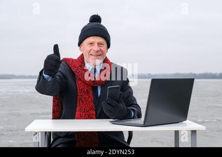 elderly gray-bearded businessman in suit, smiling while talking on smartphone Stock Photo