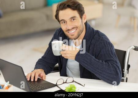 disabled young man using laptop and drinking coffee Stock Photo